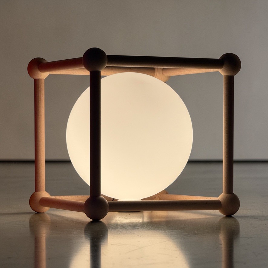 A beech frame holds a glowing opal glass globe